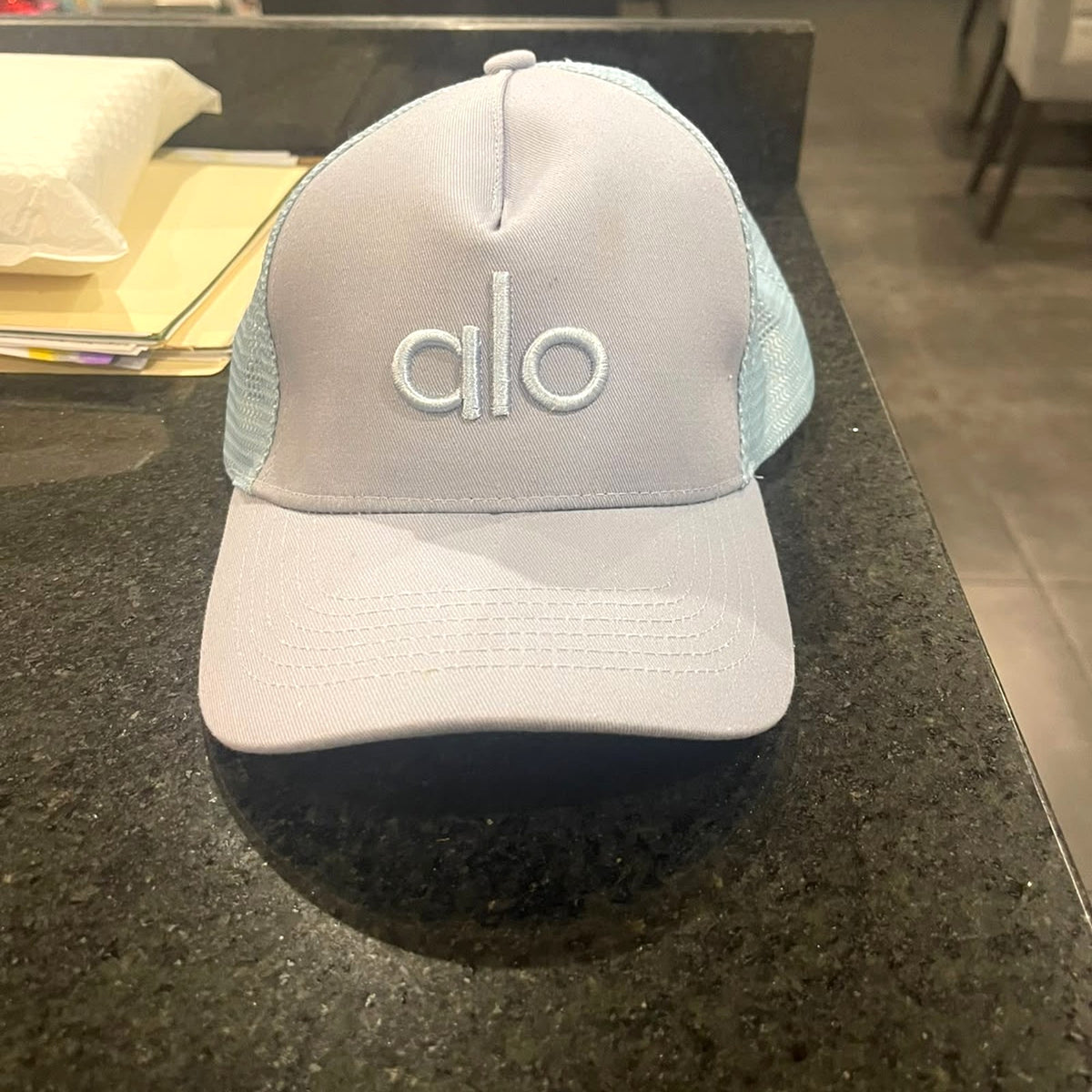 Alo Yoga District Trucker Hat in Sky Blue on a counter – real photo
